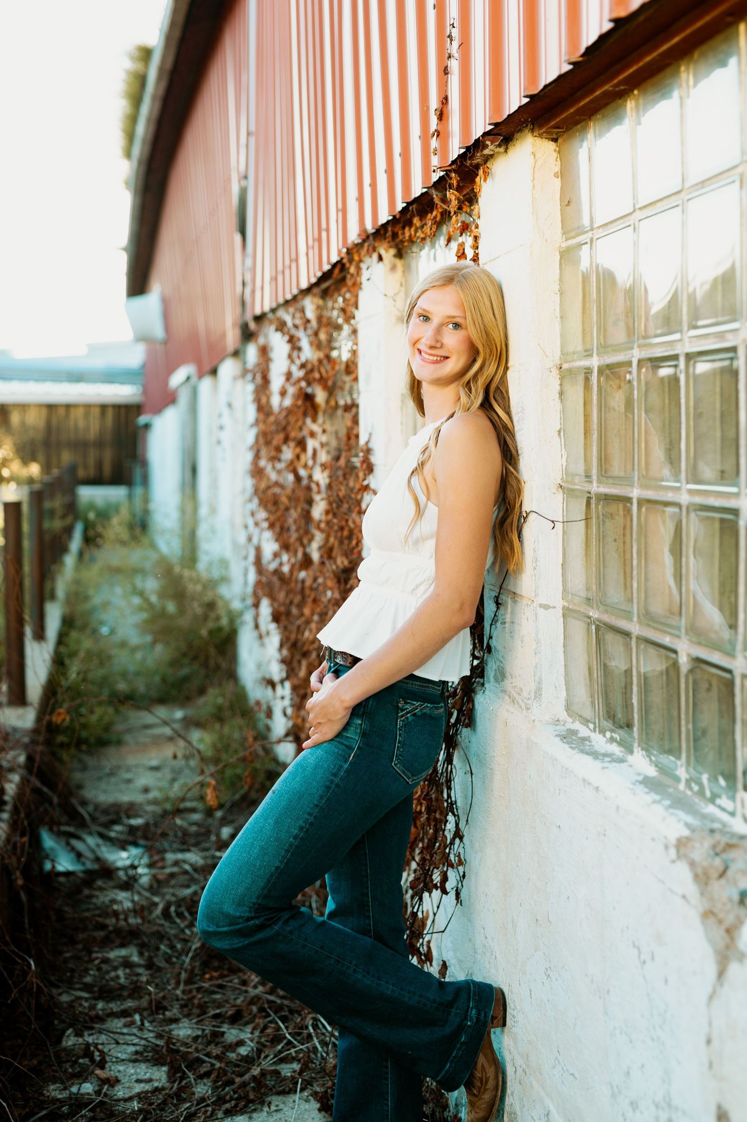 Four outdoor portrait shots showing someone in dark overalls posing against a rustic white wall with orange siding above.