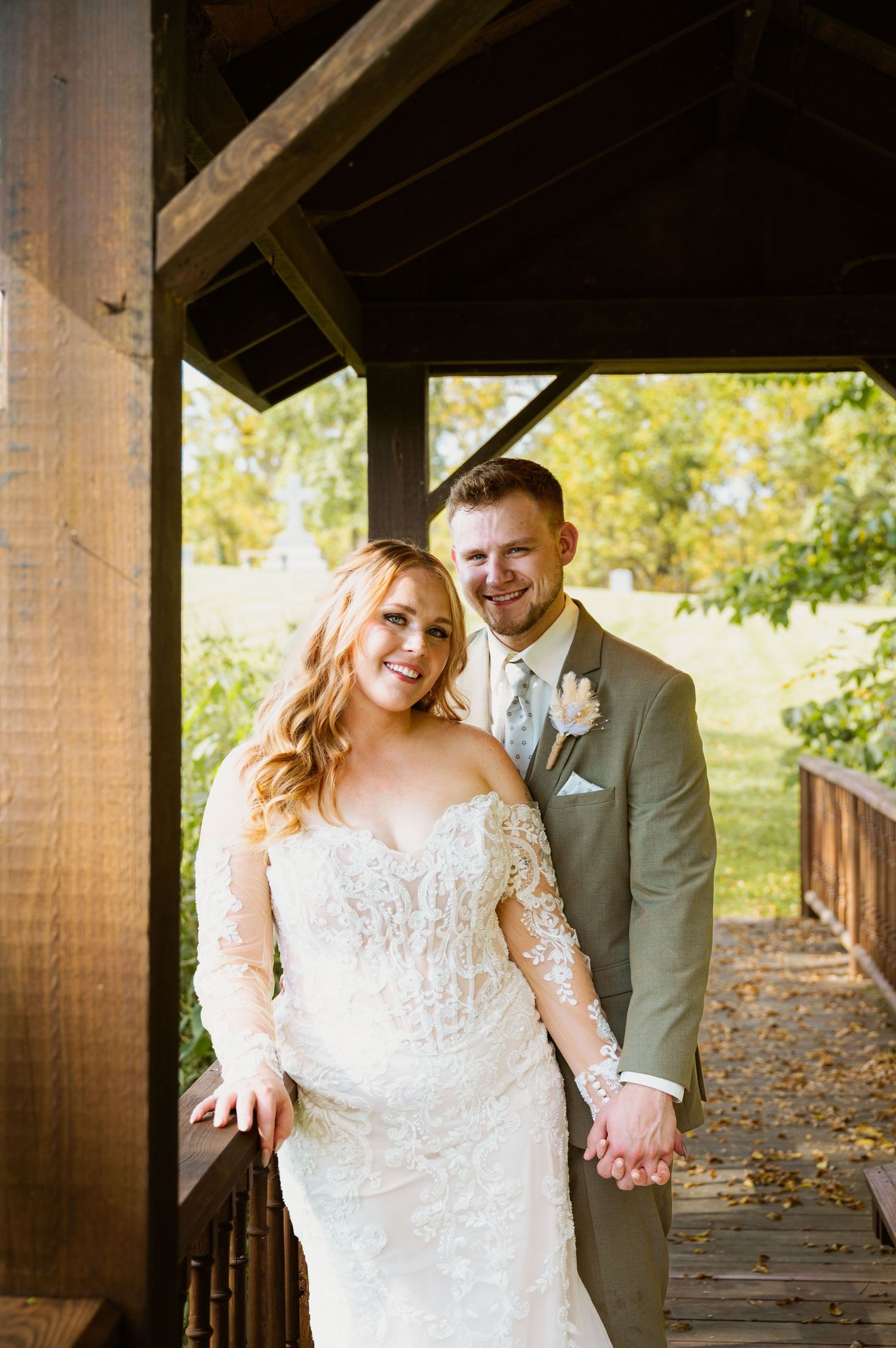 A newlywed couple poses together on a rustic wooden porch on their wedding day.