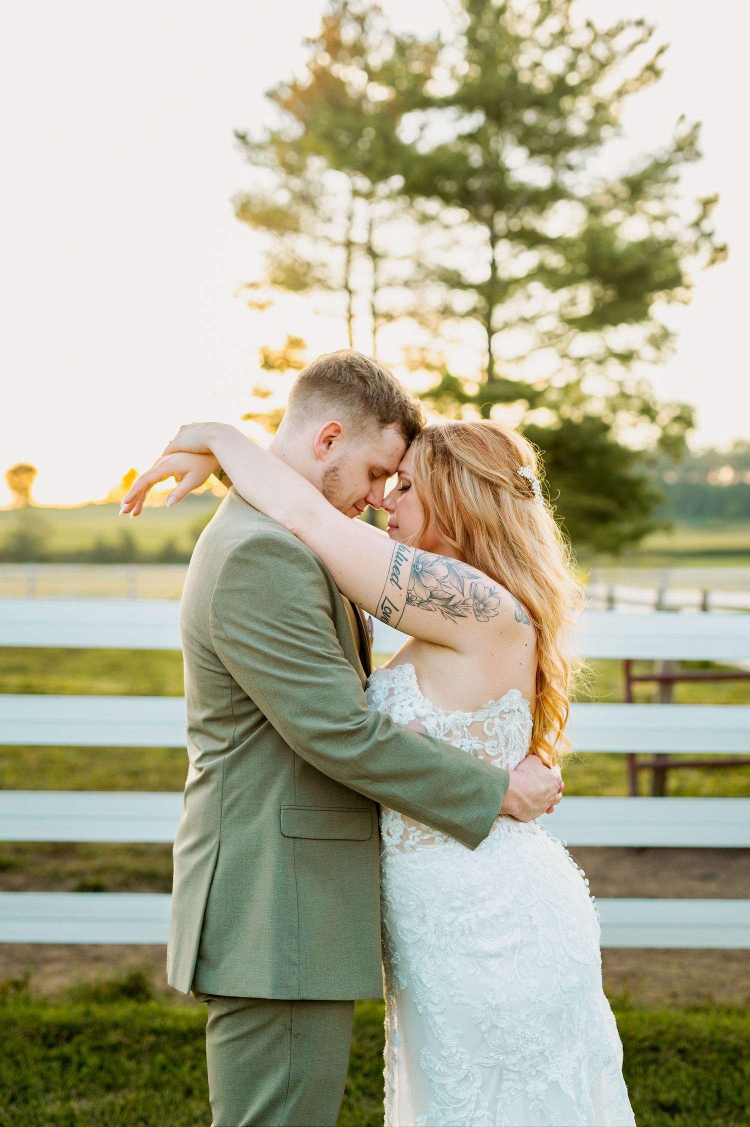 Romantic golden hour wedding portraits captured against rustic fence backdrop.