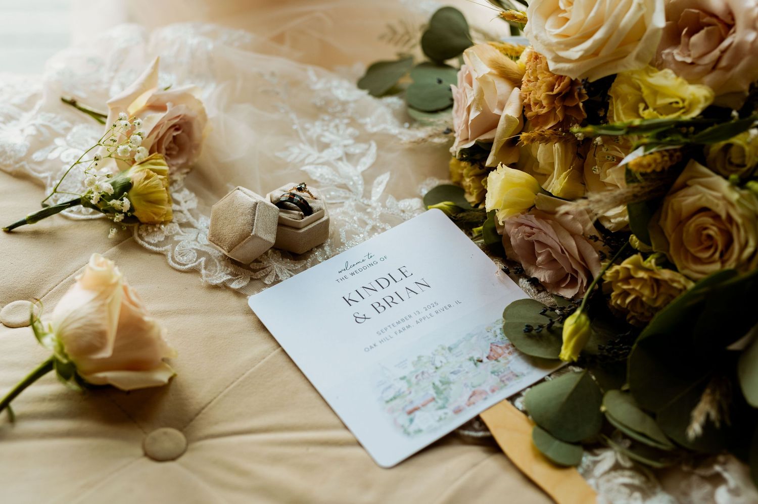 Elegant wedding stationery displayed with blush roses and greenery on light fabric background.