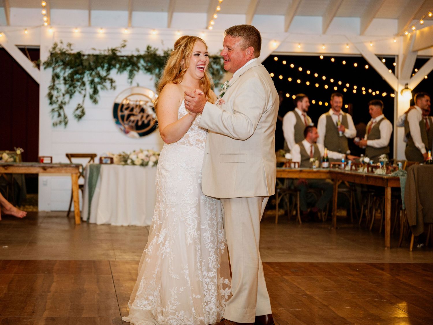 A romantic first dance moment in an elegant reception venue with string lights and greenery decorations.
