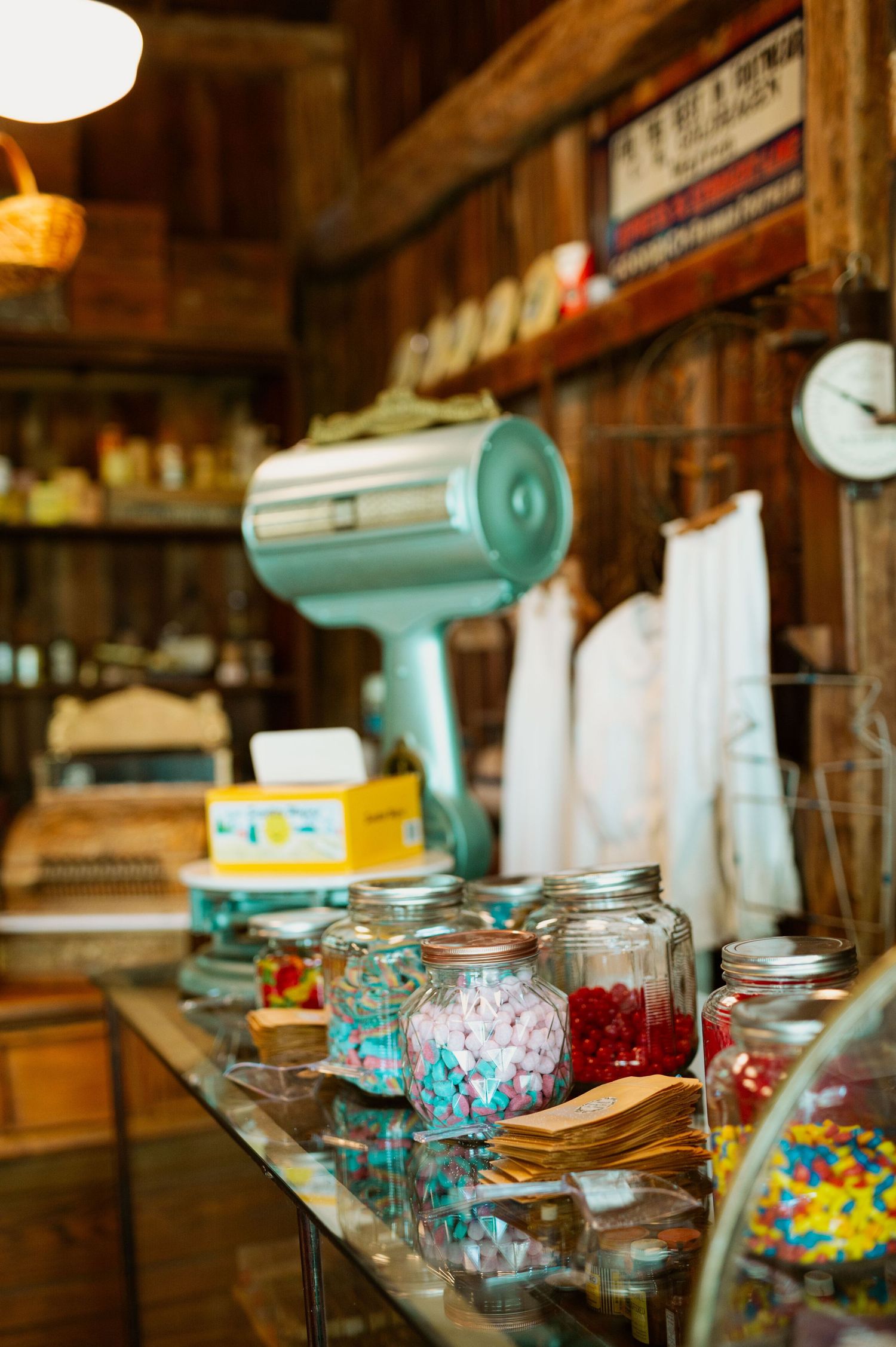 Vintage candy store counter with turquoise scale and glass jars filled with colorful treats and confections.