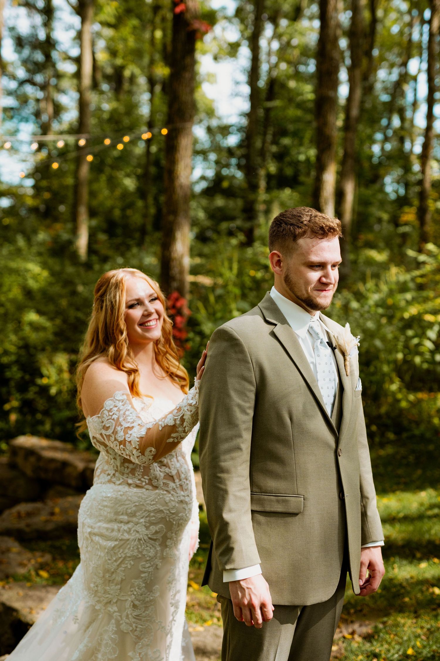 Wedding couple walking hand in hand through a lush wooded area with natural lighting.