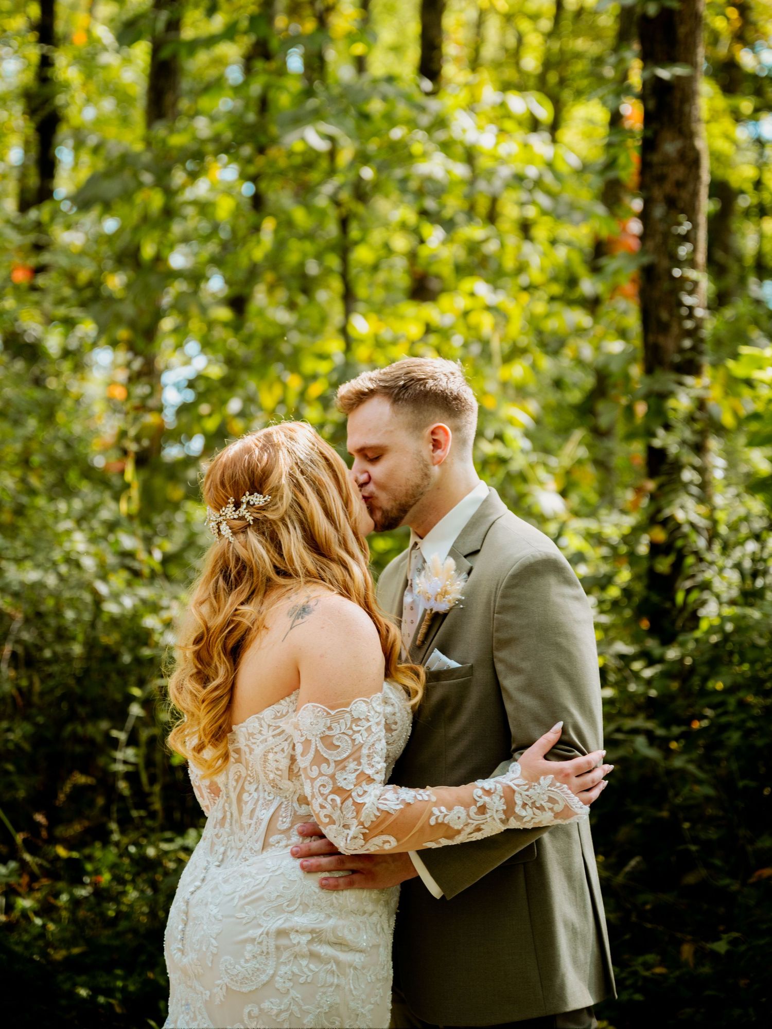 A couple embraces during their wedding photoshoot in a lush green forest.