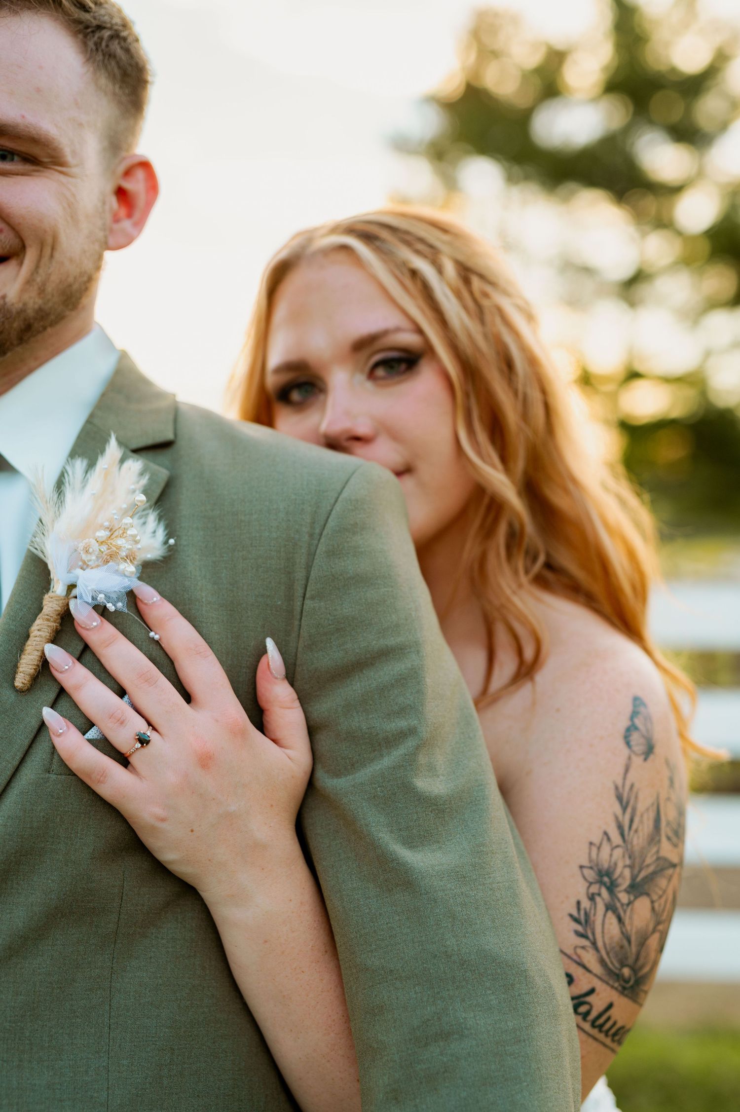 Close-up wedding portrait showing details of sage green suit and floral boutonniere.