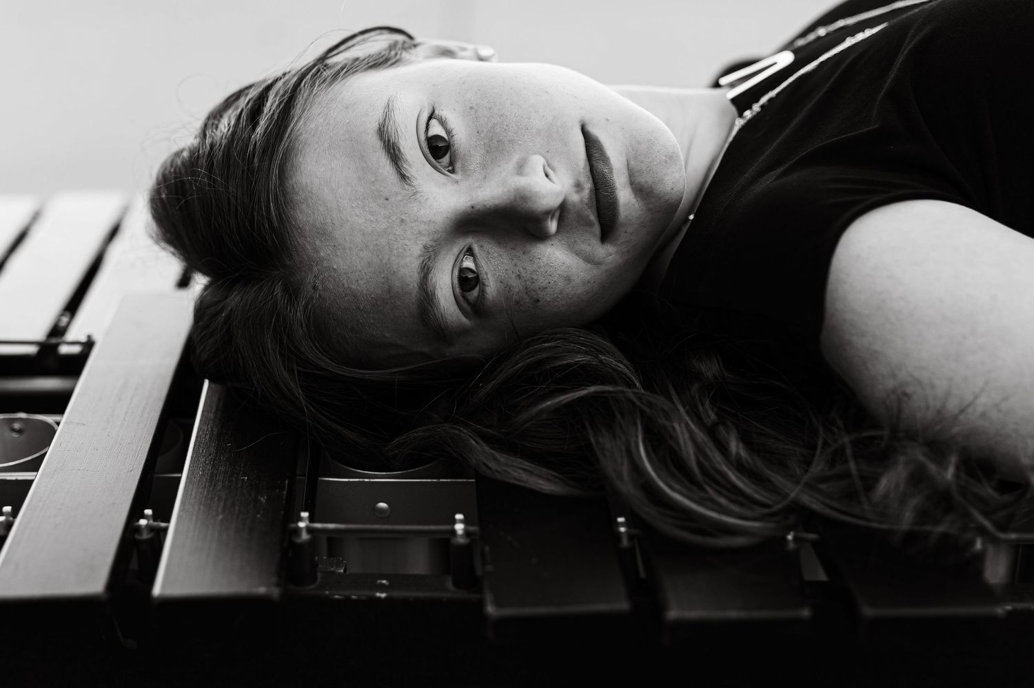 Artistic black and white portrait of woman lying on piano keys.