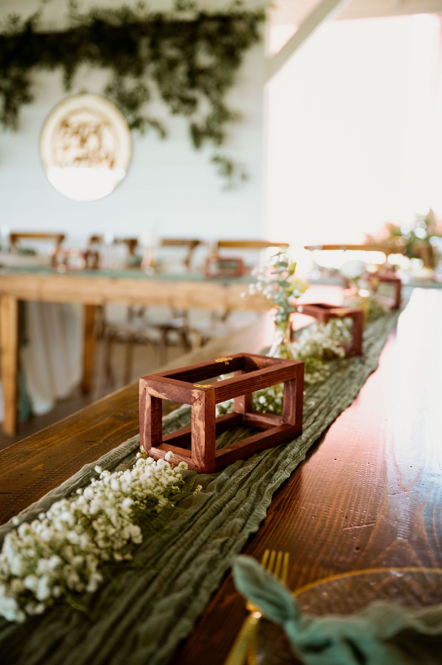Rustic wooden table decorated with delicate floral arrangements and lanterns for a wedding reception.