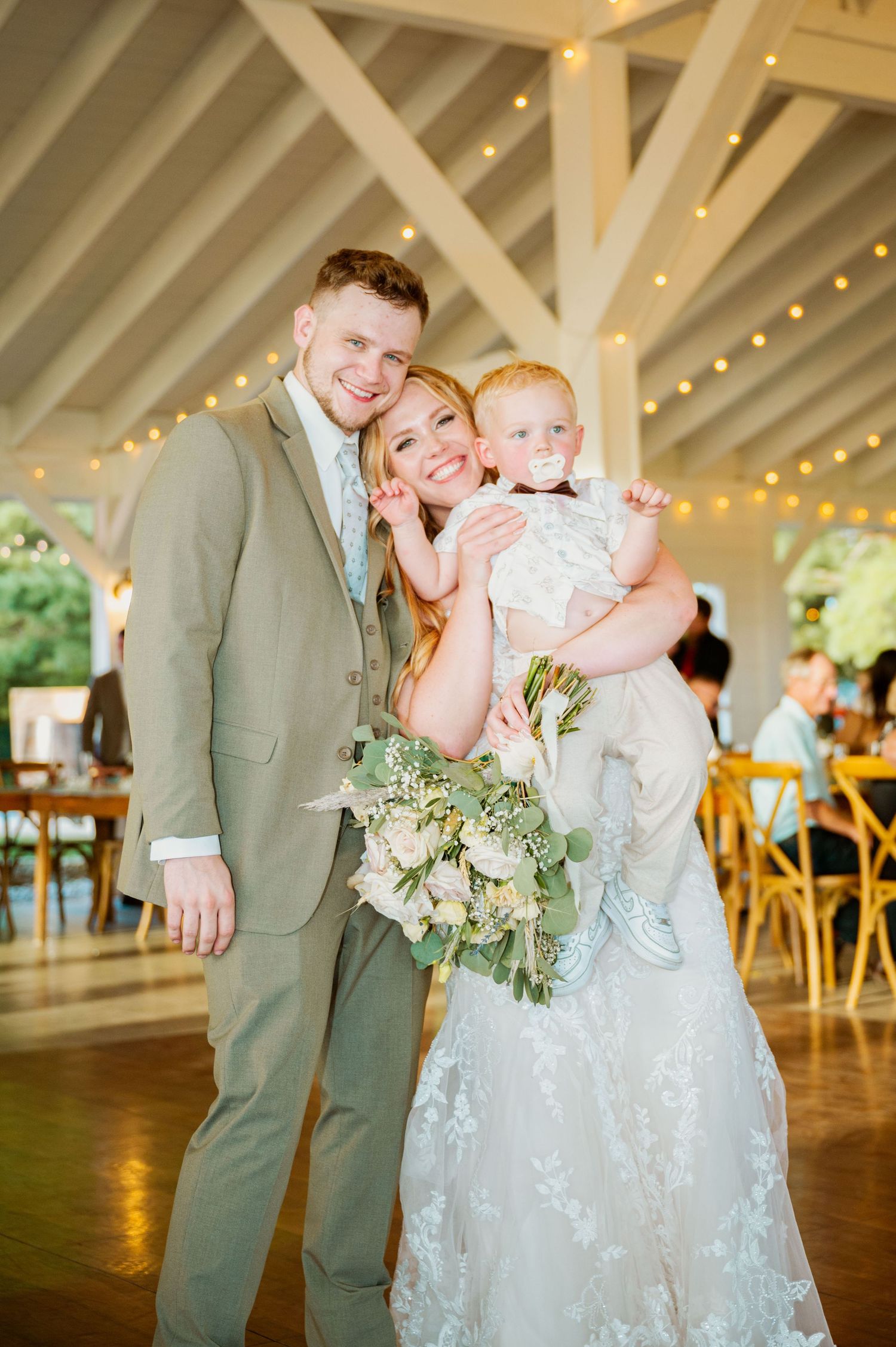 A wedding celebration in a rustic venue decorated with string lights and featuring a beautiful floral bouquet.