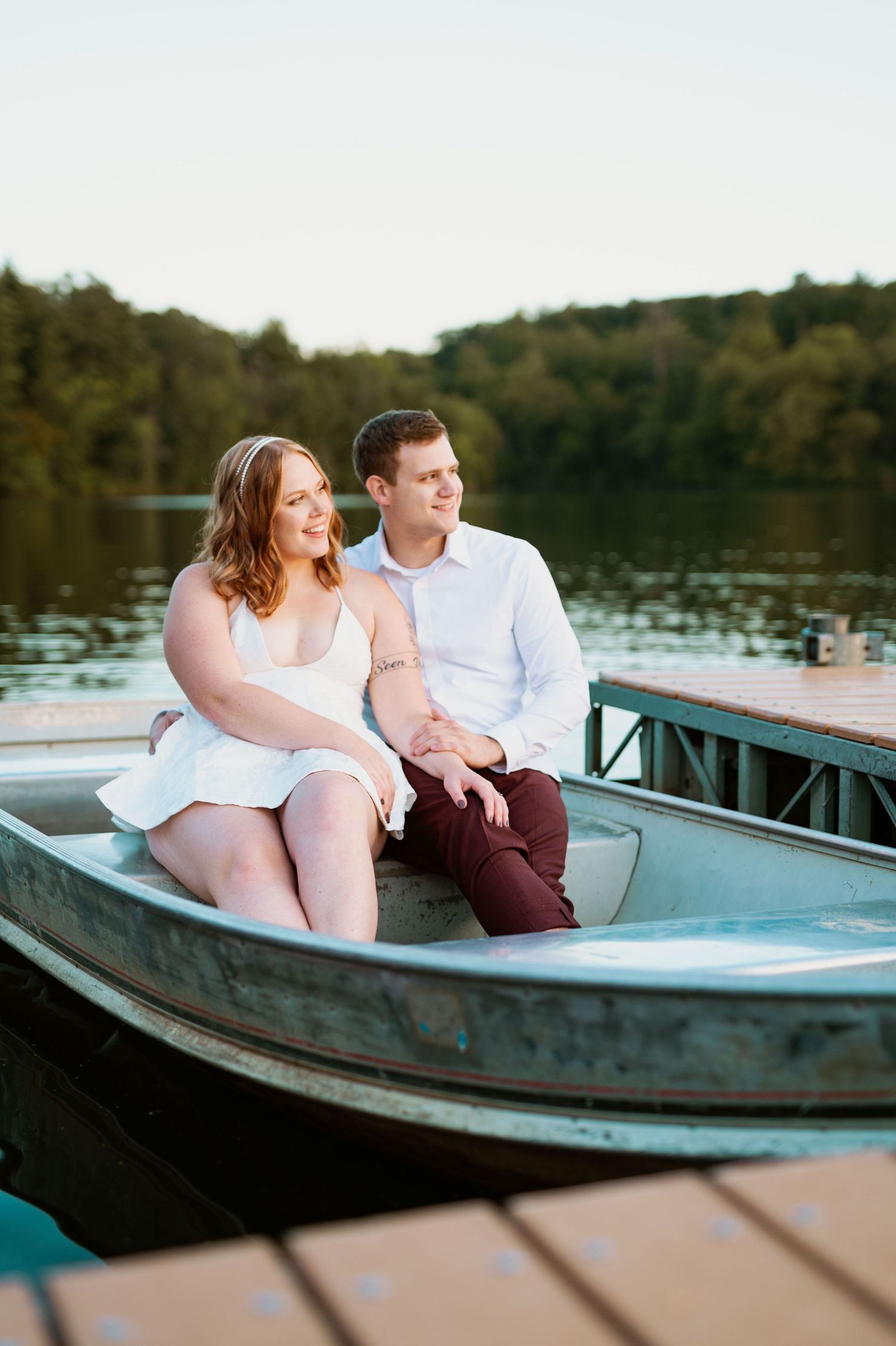 Couple sitting together in a blue rowboat on a peaceful lake at sunset.