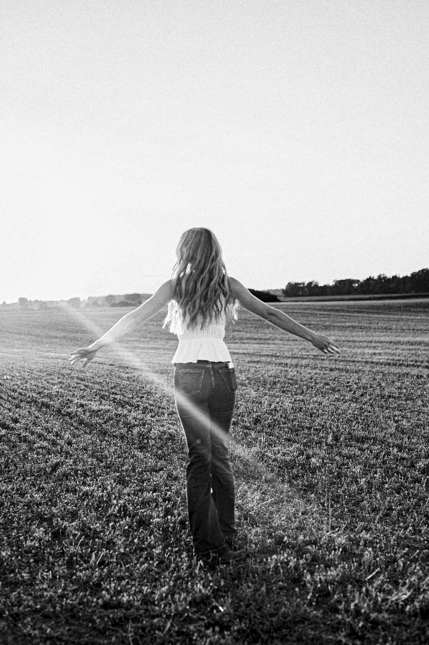 Black and white sequence showing a person with flowing hair dancing freely in an open field.