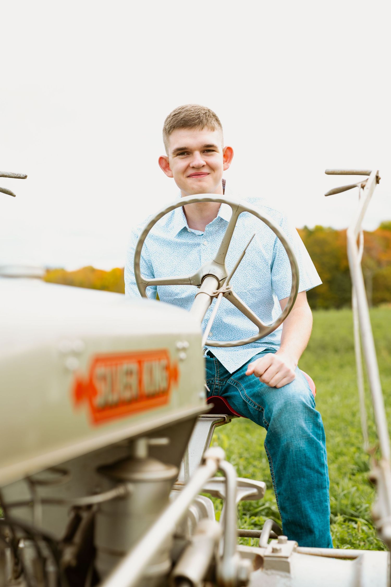 Close-up view of someone seated at the steering wheel of a classic Silver King tractor.
