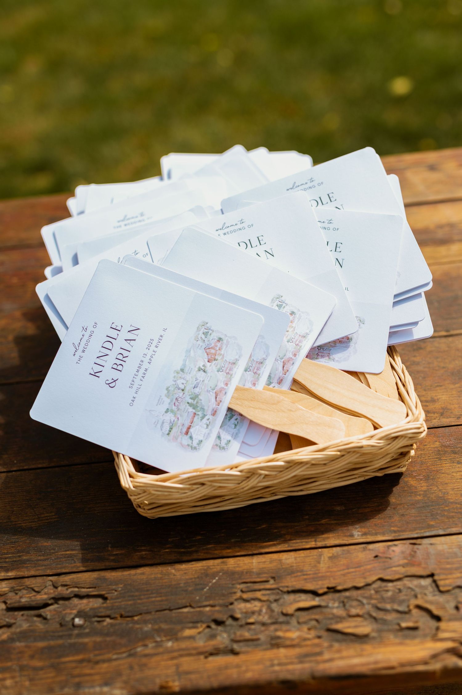 Wedding invitation cards arranged in a woven basket on a wooden surface.