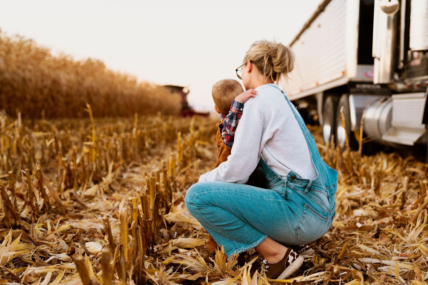 A child plays in a field of tall brown grass during golden hour.