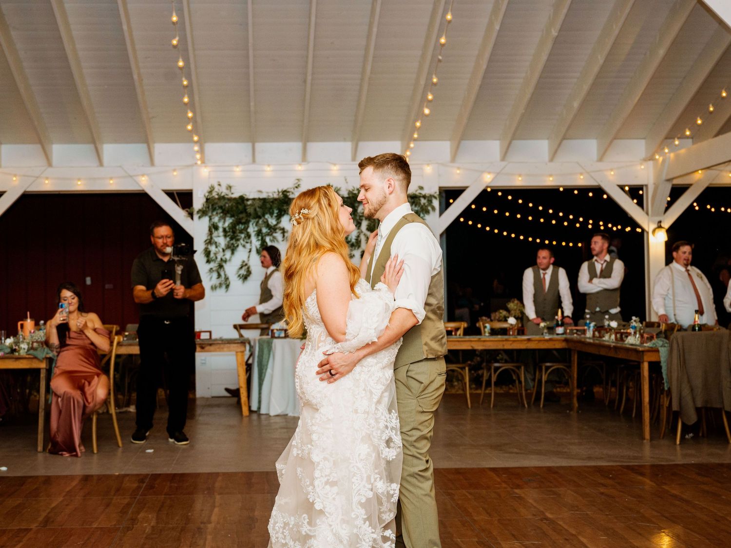 Wedding reception venue decorated with string lights and white ceiling draping.