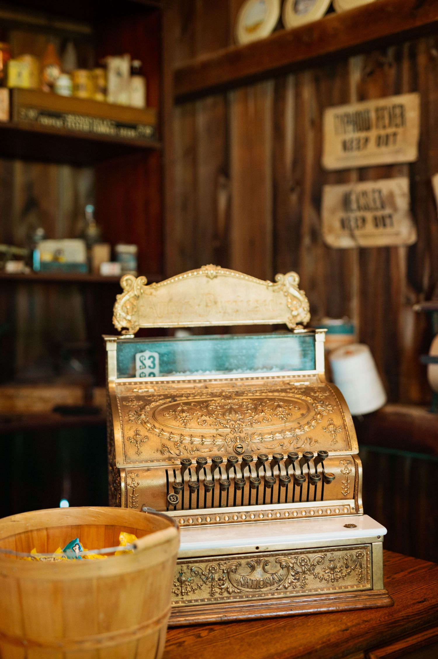 Vintage ornate cash register displayed in rustic wooden setting.