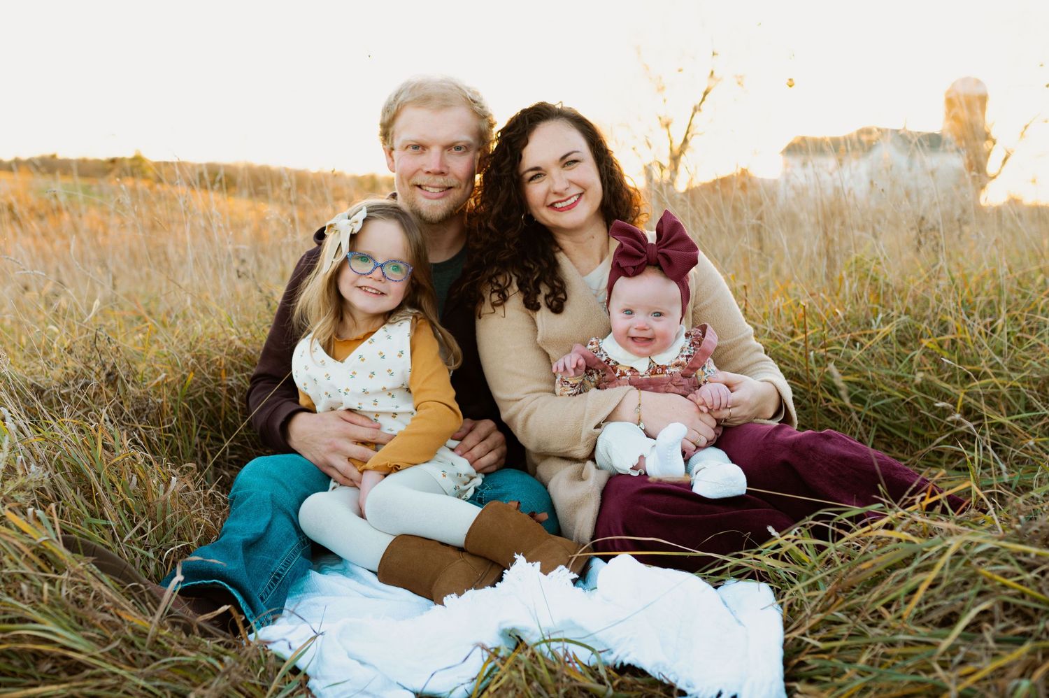 A group sits together in a grassy field during golden hour sunset for outdoor family photos.