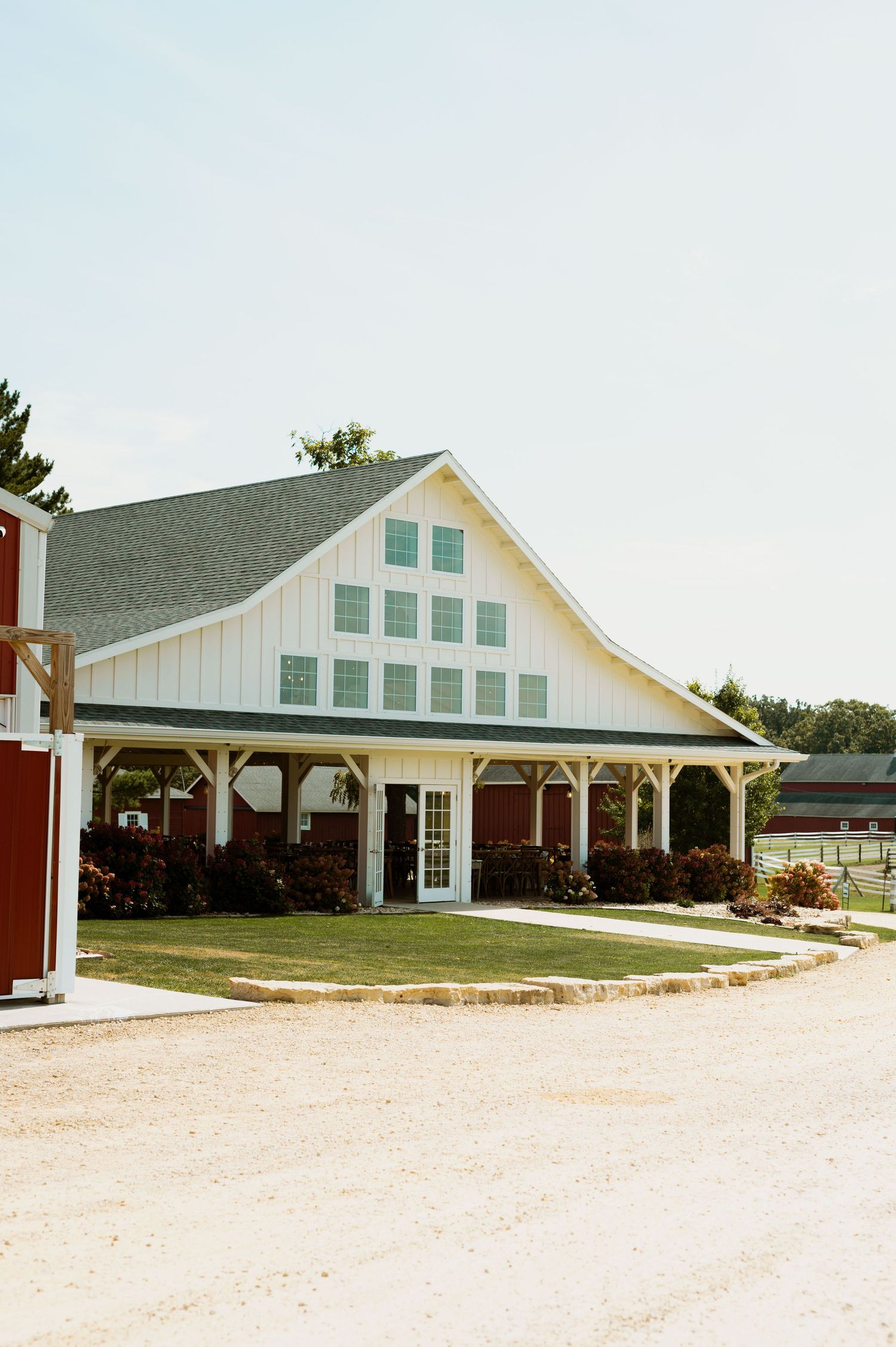 Long white modern barn-style wedding venue with multiple windows and covered porch area.