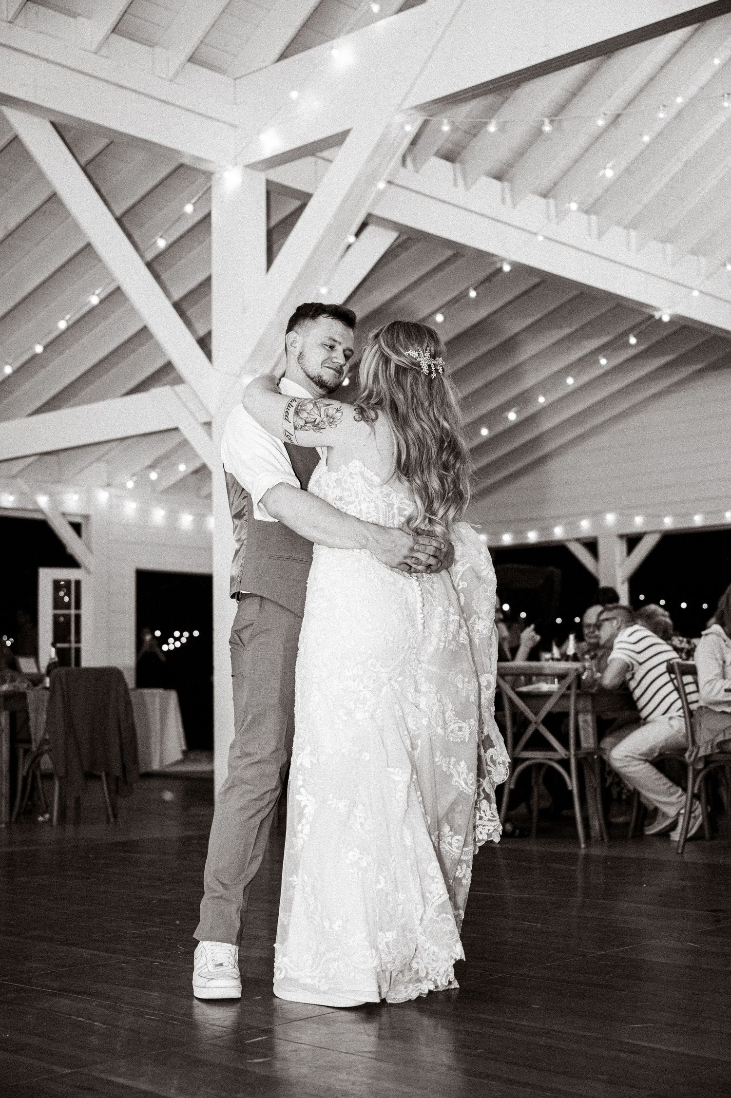 Romantic first dance moment under a white pavilion with twinkling lights at an evening wedding reception.