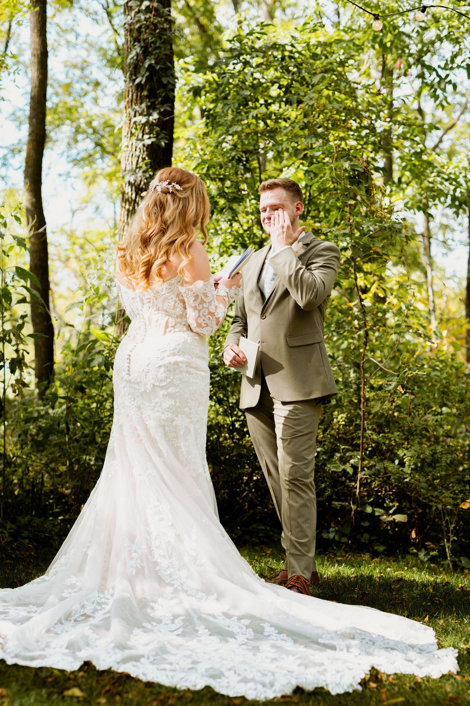 A romantic first look moment between a couple in a lush forest setting with golden sunlight filtering through trees.