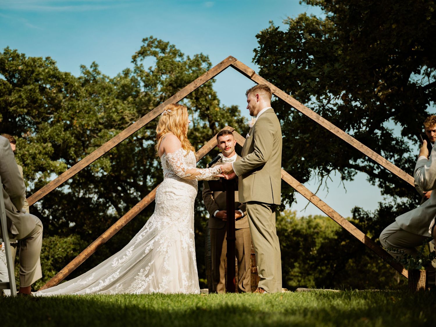 Wedding couple performing a playful dance move outdoors against a blue sky.