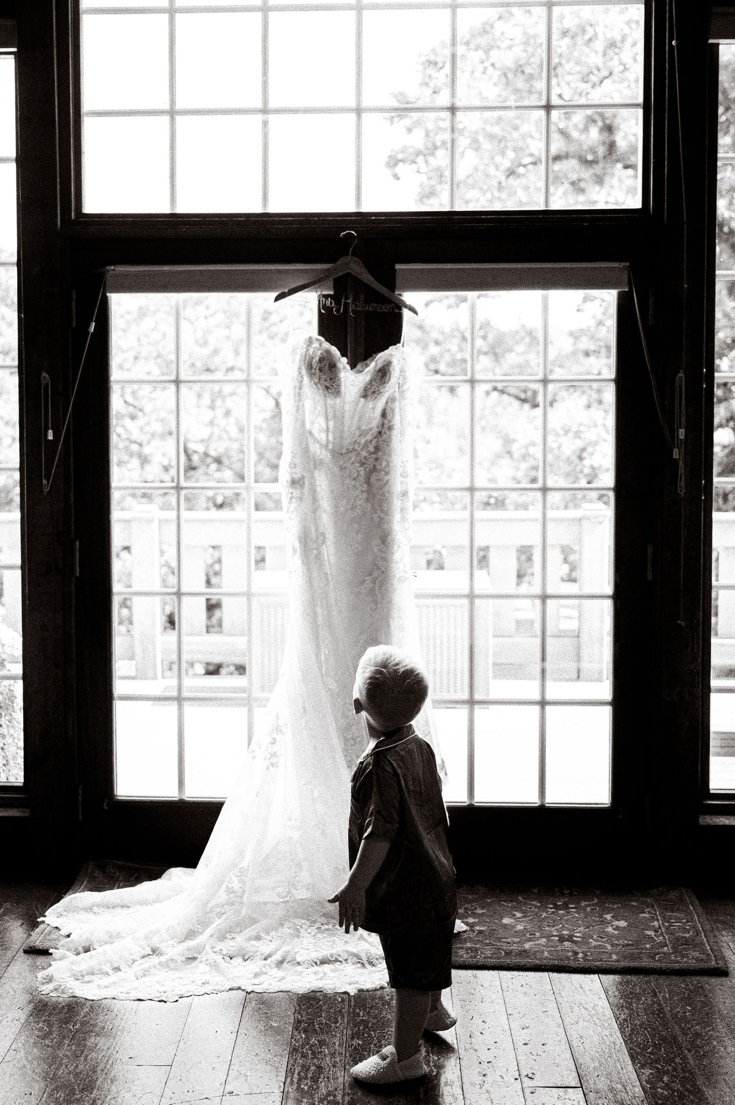 Wedding dresses hanging by windows in an elegant room with natural light.