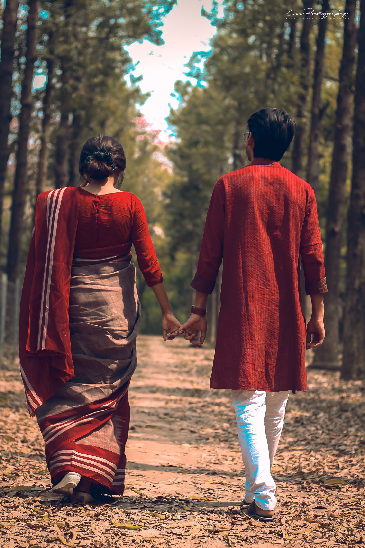 Two people in traditional Indian attire walking through a forest path.