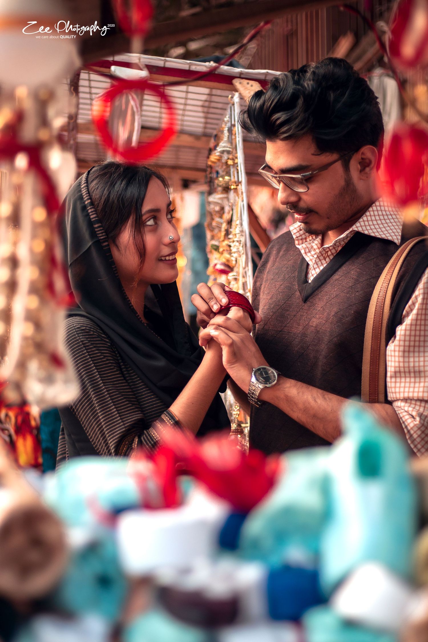 Young couple sharing a romantic moment while shopping at a colorful market with decorative items in the background.
