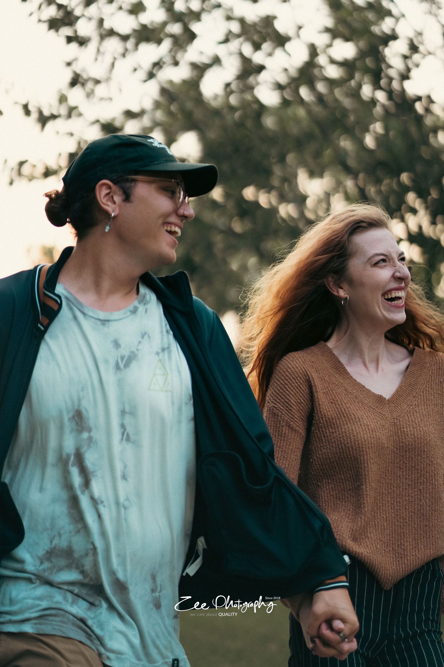 Happy couple laughing together while walking outdoors during sunset.