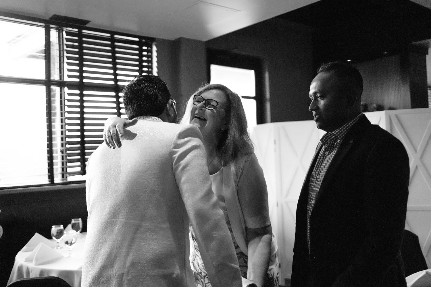 A collage of black and white wedding photographs showing emotional embraces and candid moments during the celebration.