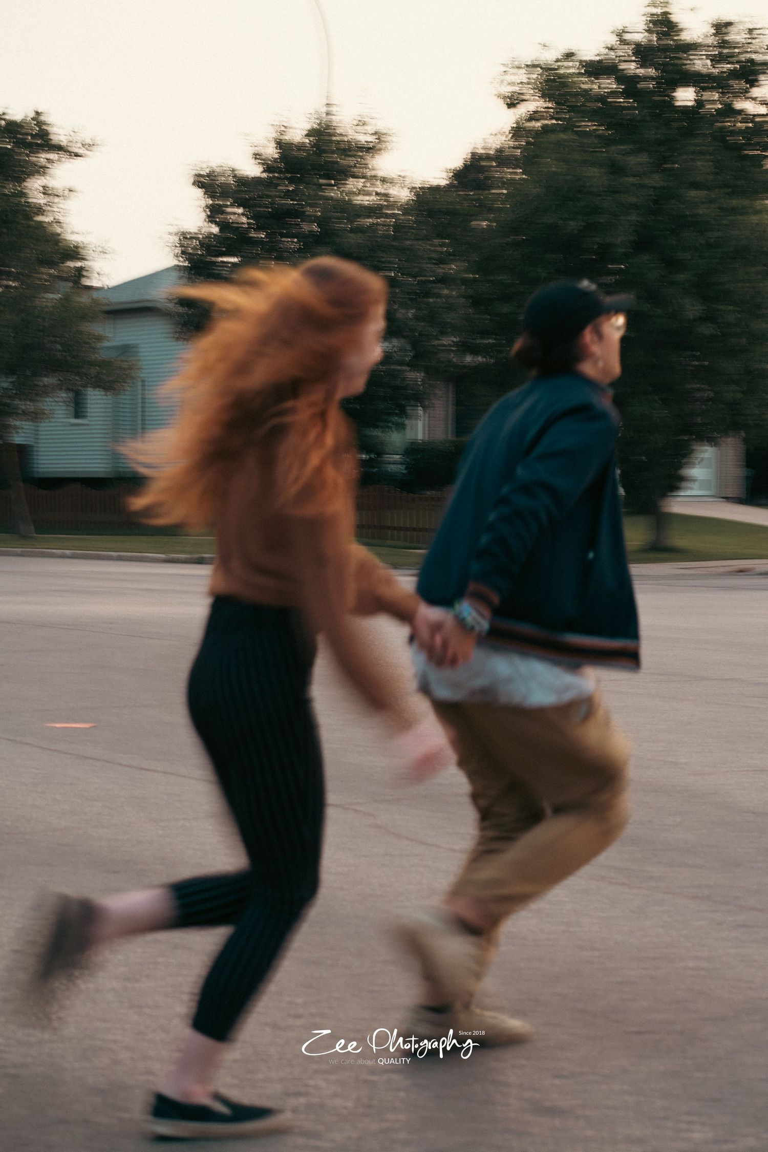 Couple running and holding hands on street at sunset with motion blur effect.