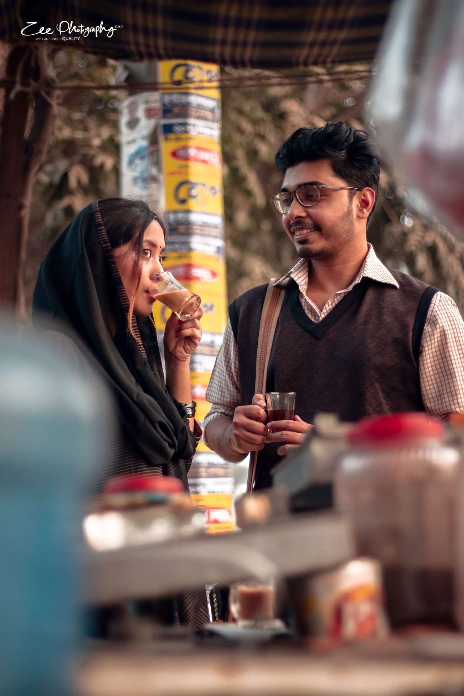 A couple shares laughter and tea at an outdoor cafe, captured in a warm cinematic style.