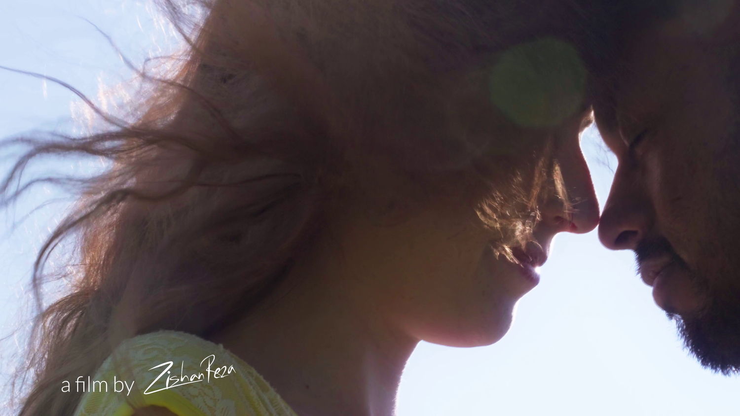 Intimate silhouette portrait of two people in close embrace with sunlight behind them.