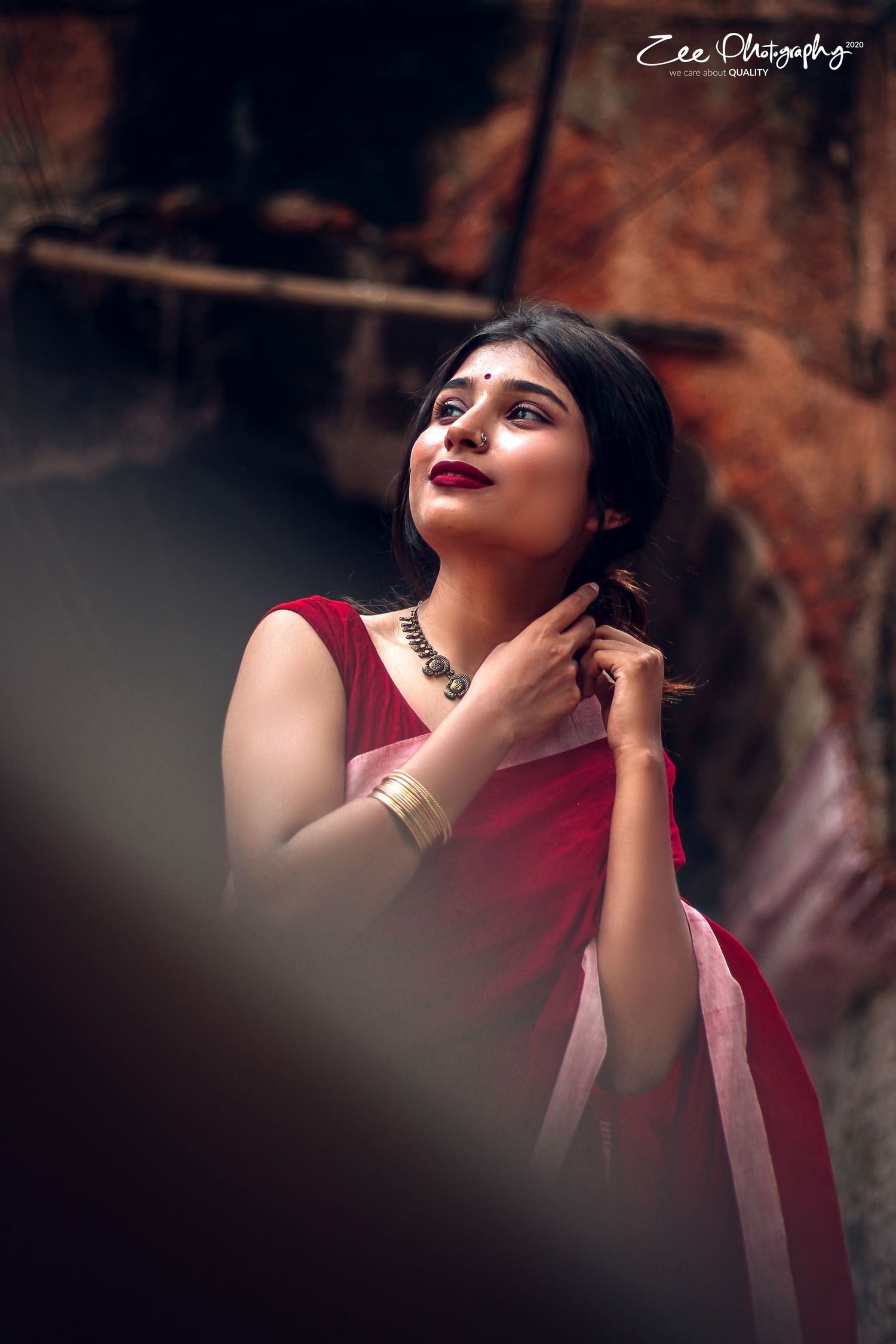 Artistic portrait in red traditional saree with dramatic shadows and moody lighting.