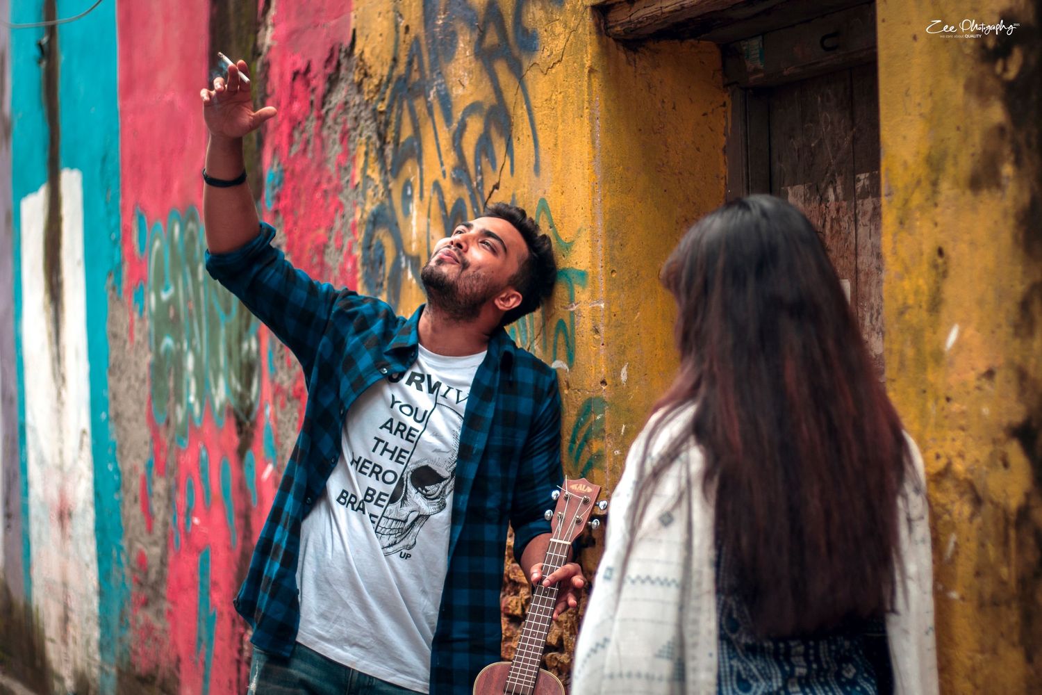 Urban photoshoot against colorful graffiti wall capturing candid interactions.