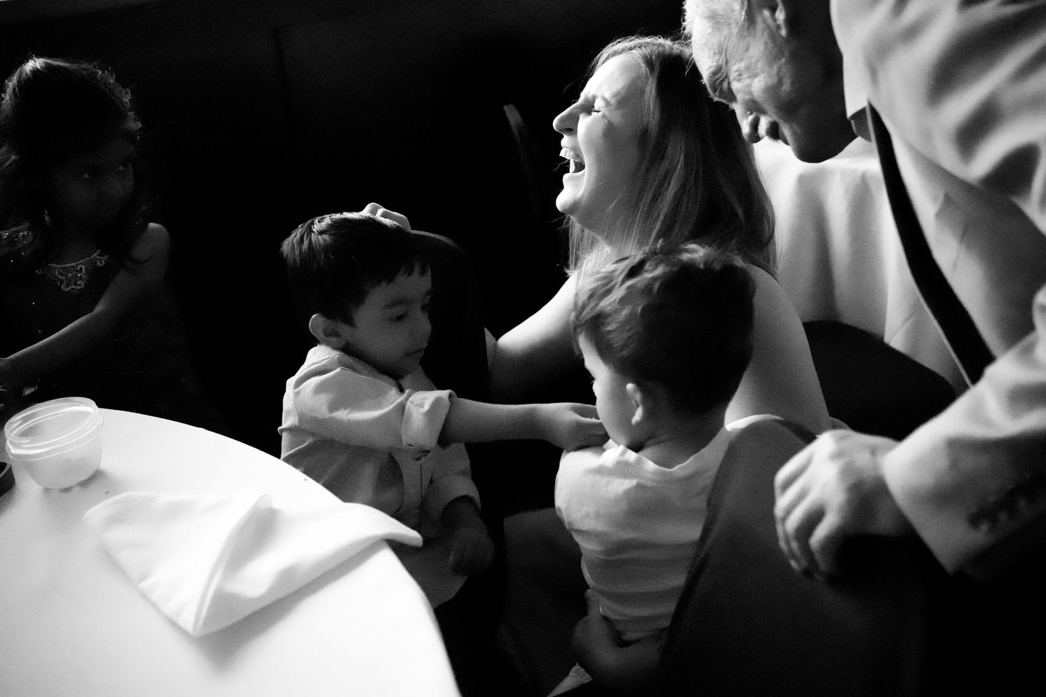 A candid black and white moment of family interaction during a joyous gathering.