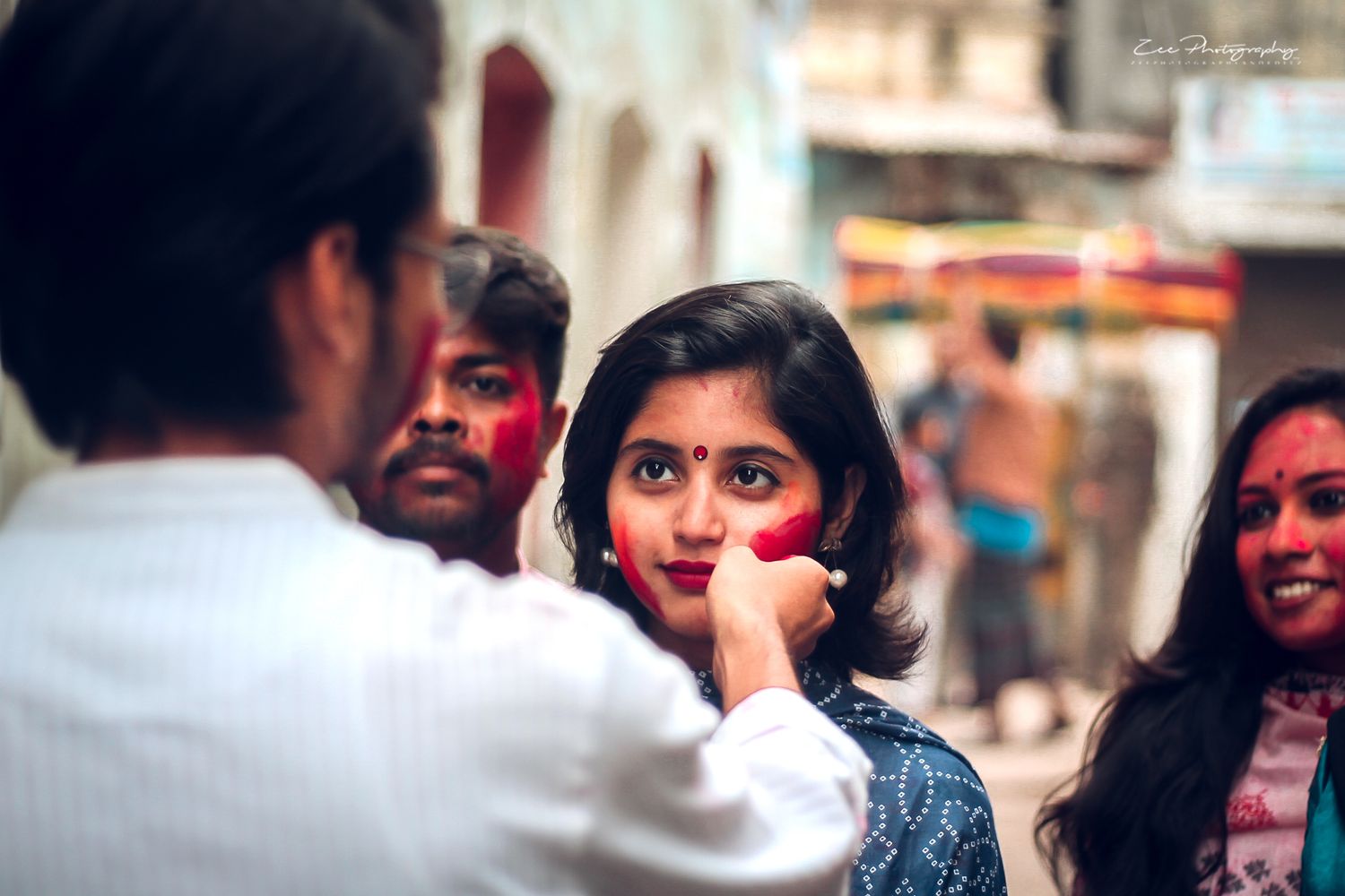 People celebrating Holi festival with colorful powder in an urban setting.