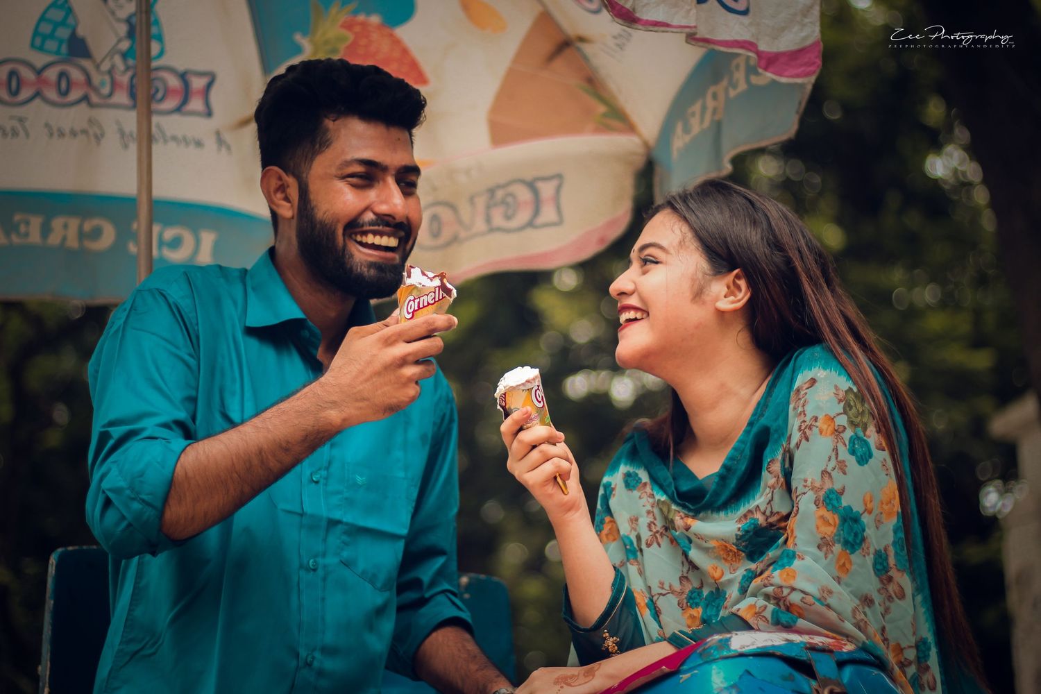 A couple sharing ice cream cones and laughing together outdoors.