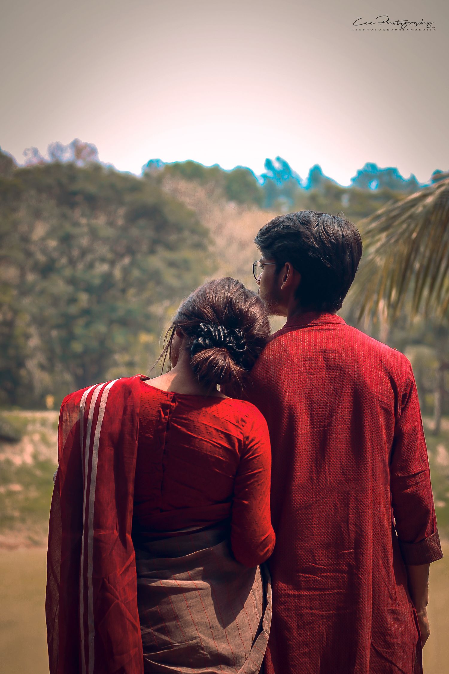 Couple wearing matching red outfits in outdoor portrait session at dusk.