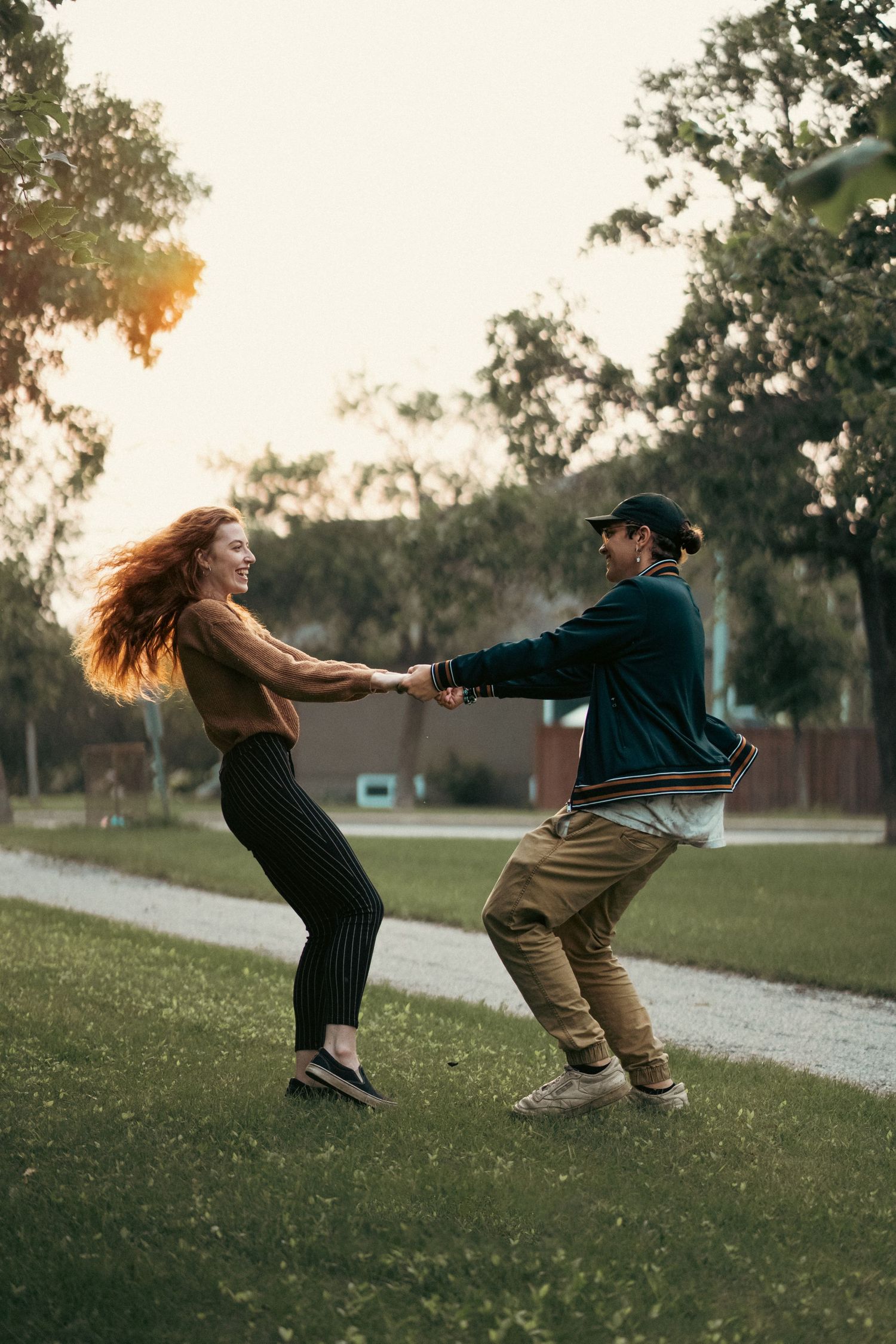 A couple dancing together on a grassy area during golden hour as her hair flows in the wind.