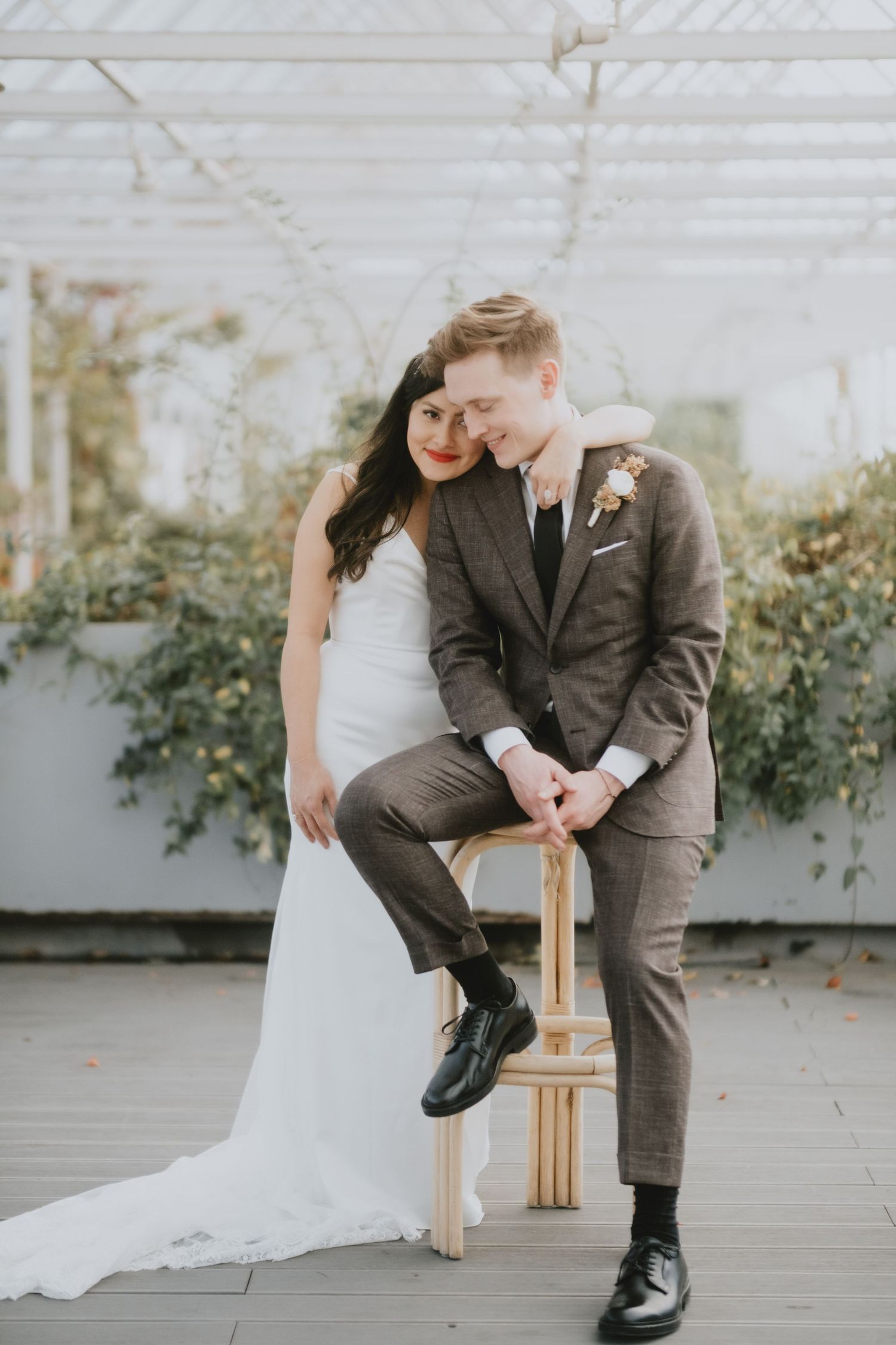 Romantic wedding portrait of couple posing with greenery backdrop.