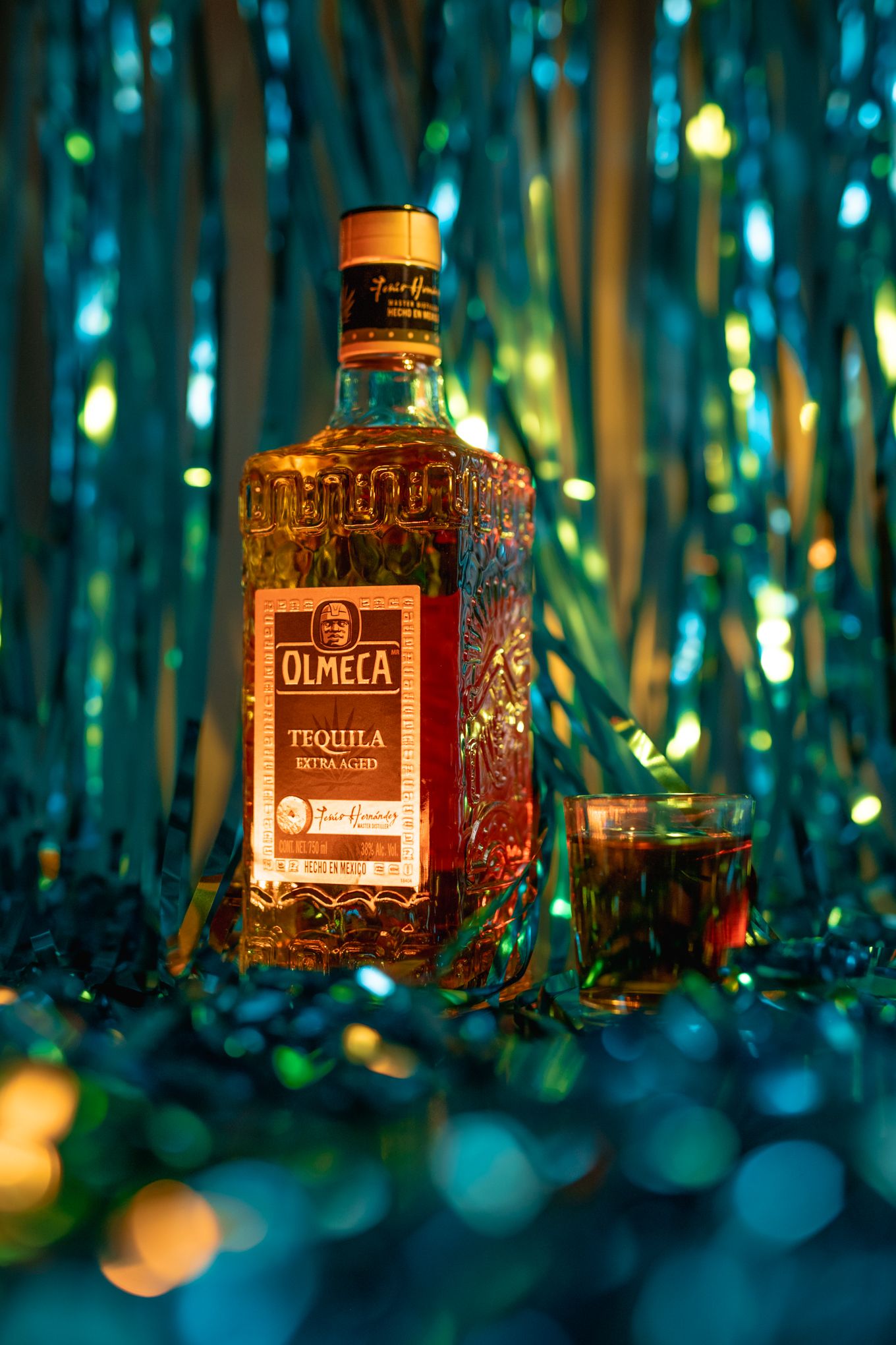 Olmeca tequila bottle photographed against mystical blue bokeh backdrop.