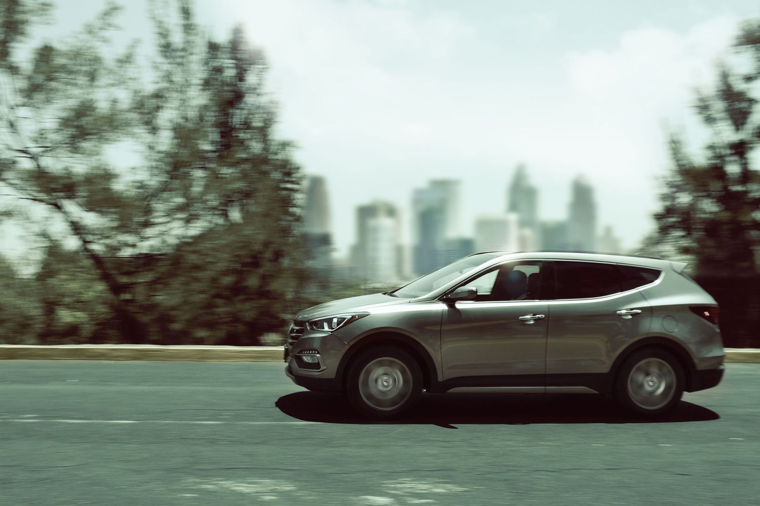 Sequence of black and white photos showing a sports car driving on a blurred background with trees and buildings.