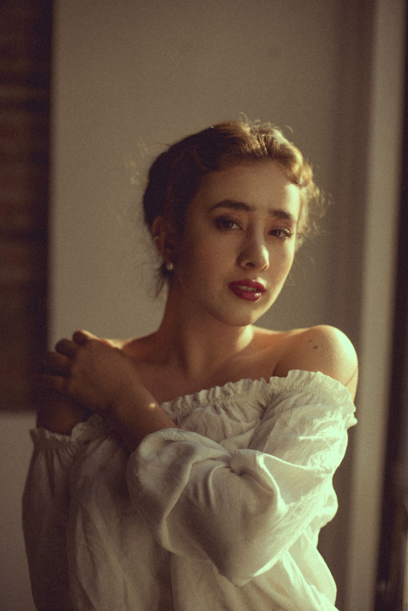 Romantic portrait in white off-shoulder dress with soft lighting.