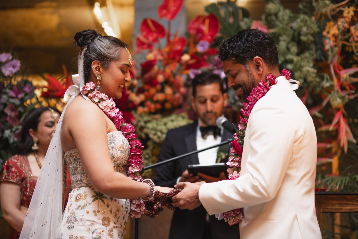 Traditional wedding ceremony with couple exchanging rings underneath floral decorations.