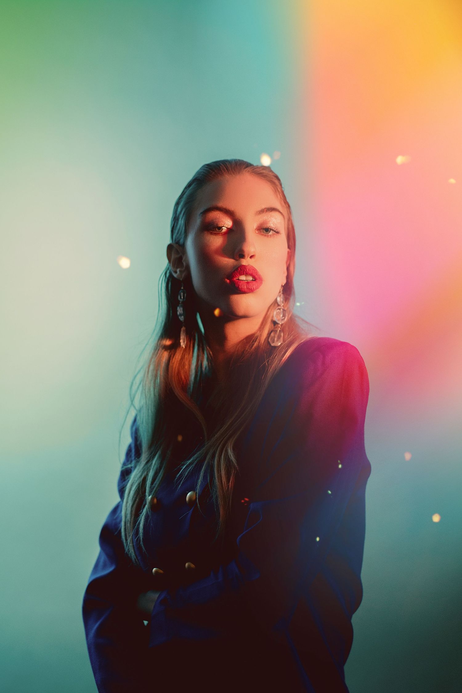 Fashion portrait with colorful gradient background and sparkle effects in dreamy lighting.
