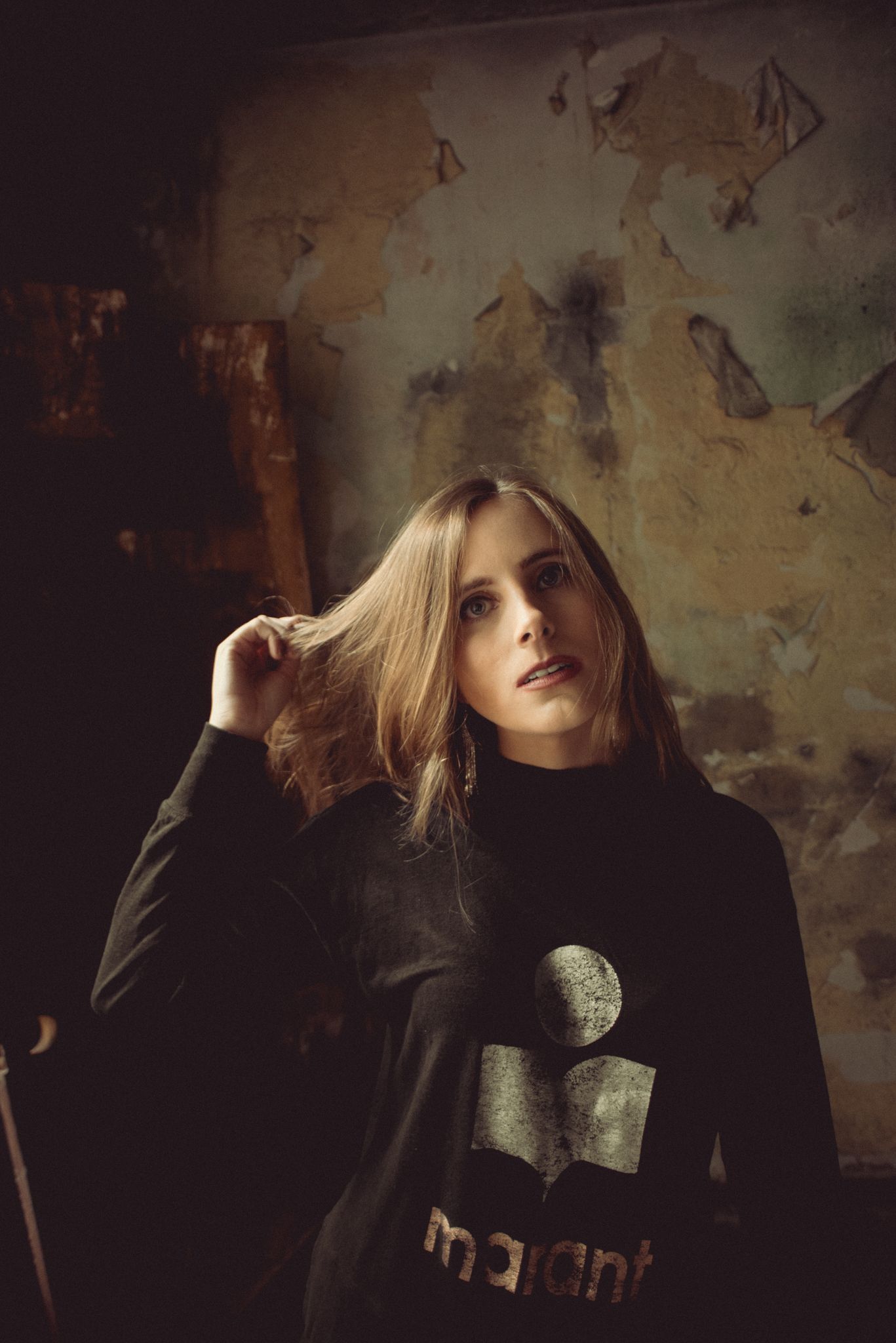 Moody indoor portrait with vintage worn wall background.