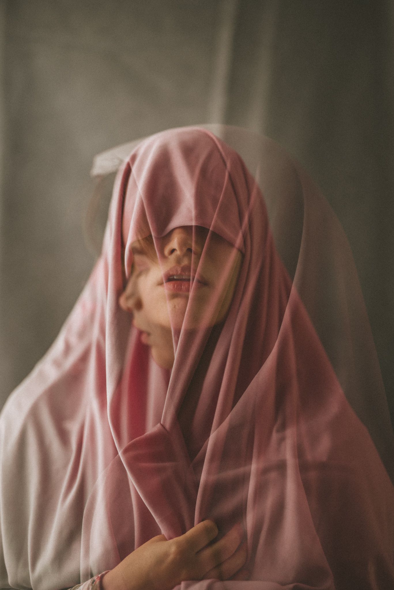 Artistic portrait showing person in pink hijab with soft lighting and dreamy atmosphere.
