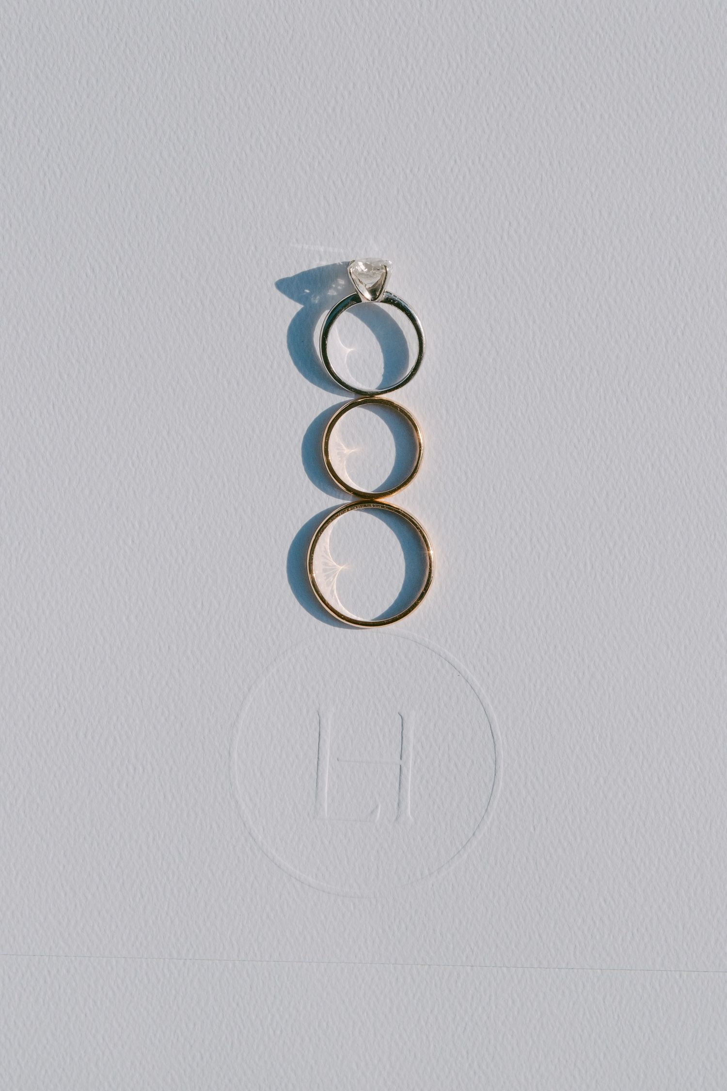 Three engagement or wedding rings casting shadows on a white background with a minimalist layout.