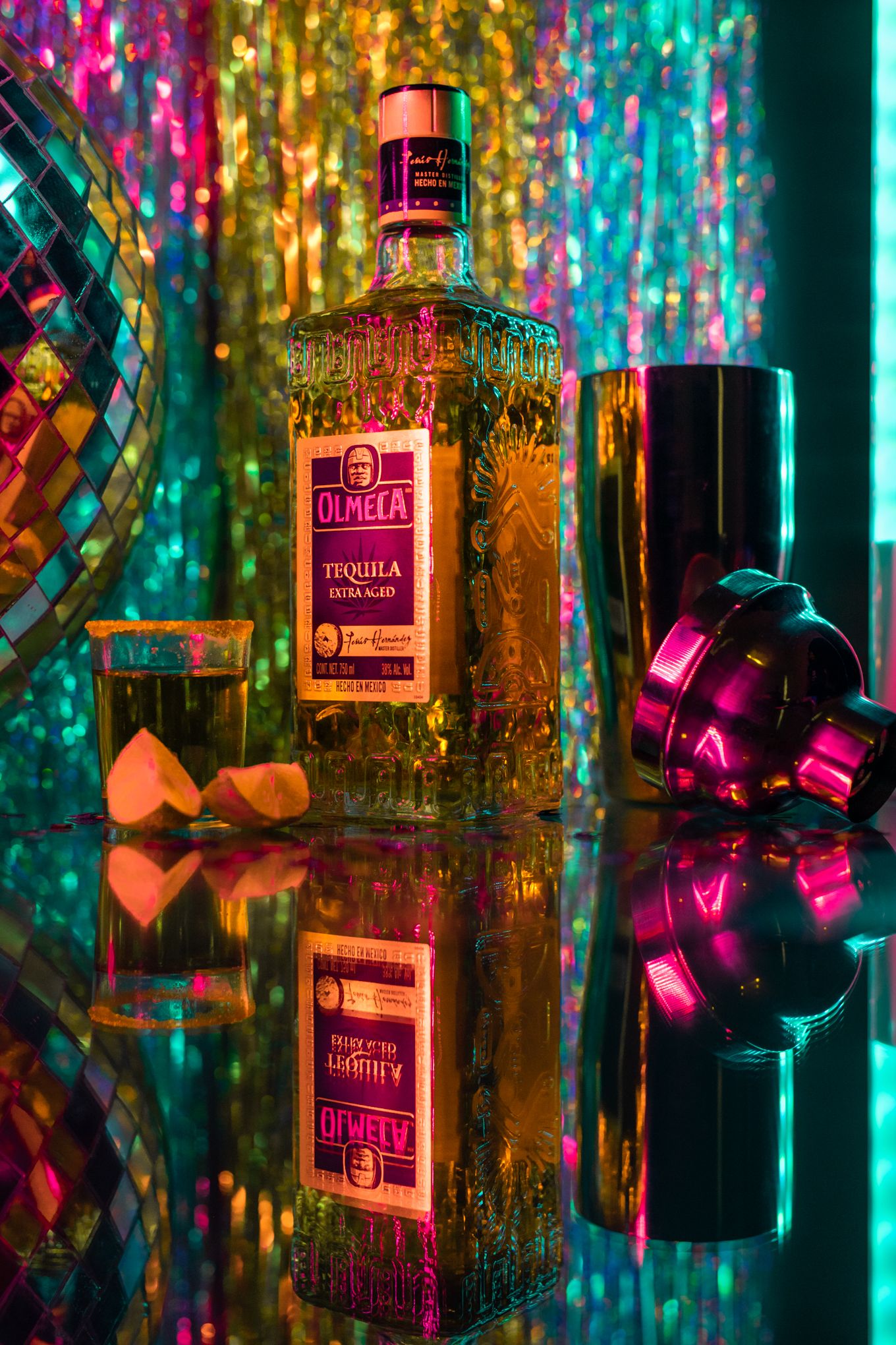 Olmeca tequila bottle with colorful bokeh lights and mirror reflection creating vibrant party atmosphere.