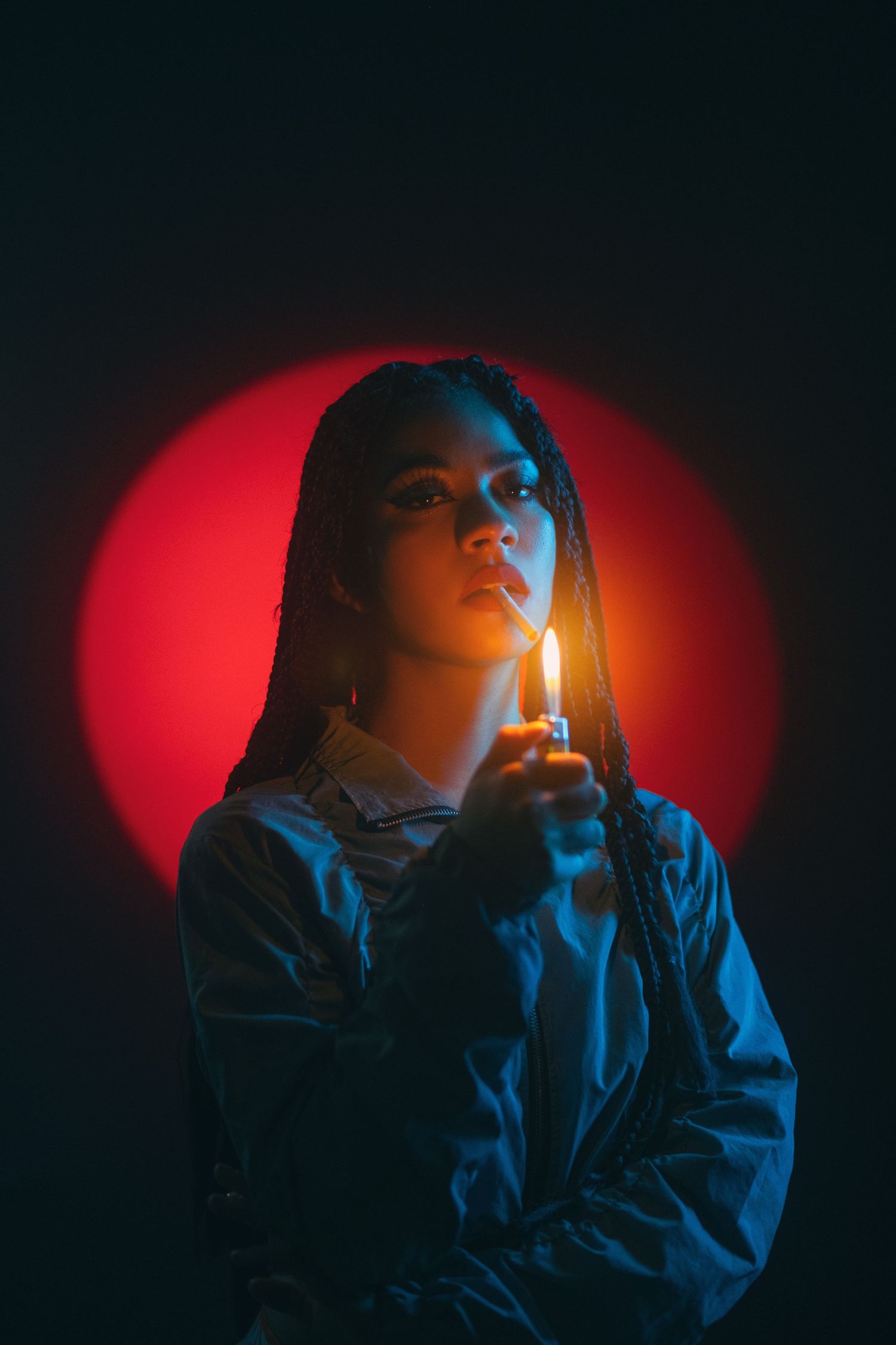 Moody portrait with red circular light and candlelight against dark background.